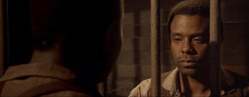 Movie still from “Dead for a Dollar” (2022), directed by Walter Hill – A man looking into a mirror while standing next to a wall; Close Up shot, Over the shoulder angle