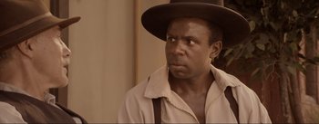 Movie still from “Dead for a Dollar” (2022), directed by Walter Hill – A man in a hat and a shirt looking to his left; Close Up shot, Over the shoulder angle