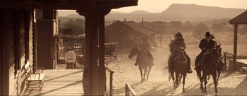 Movie still from “Dead for a Dollar” (2022), directed by Walter Hill – A man riding a horse in the middle of a dirt road; Wide shot, Low angle