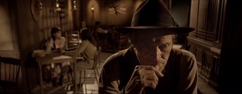 Movie still from “Dead for a Dollar” (2022), directed by Walter Hill – An older man wearing a hat sitting in front of a window; Close Up shot, Over the shoulder angle