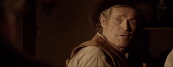 Movie still from “Dead for a Dollar” (2022), directed by Walter Hill – An older man wearing a cowboy hat and vest; Close Up shot, Over the shoulder angle