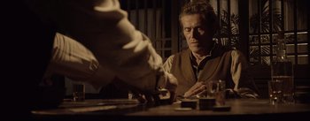 Movie still from “Dead for a Dollar” (2022), directed by Walter Hill – A man sitting in front of a table; Medium shot, Over the shoulder angle