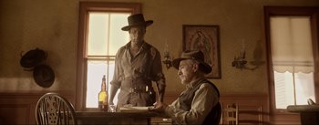 Movie still from “Dead for a Dollar” (2022), directed by Walter Hill – Two men in a room with a painting on the wall behind them; Medium shot, Low angle