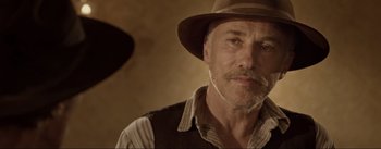 Movie still from “Dead for a Dollar” (2022), directed by Walter Hill – An older man wearing a hat and a vest; Close Up shot, Over the shoulder angle