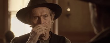 Movie still from “Dead for a Dollar” (2022), directed by Walter Hill – An older man wearing a hat and smoking a cigarette; Close Up shot, Over the shoulder angle