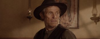 Movie still from “Dead for a Dollar” (2022), directed by Walter Hill – An older man wearing a hat and looking at the camera; Close Up shot, Over the shoulder angle