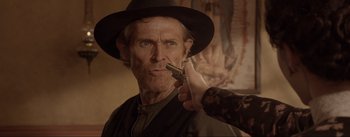 Movie still from “Dead for a Dollar” (2022), directed by Walter Hill – A man in a hat holding a gun pointed at a woman's face; Close Up shot, Over the shoulder angle