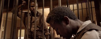 Movie still from “Dead for a Dollar” (2022), directed by Walter Hill – Two men are in a jail cell looking at each other; Medium shot, Over the shoulder angle