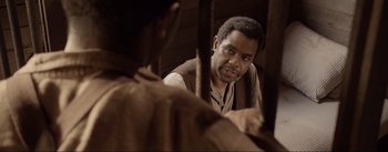 Movie still from “Dead for a Dollar” (2022), directed by Walter Hill – A man looking at another man in a brown vest; Close Up shot, Over the shoulder angle