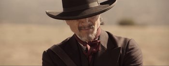 Movie still from “Dead for a Dollar” (2022), directed by Walter Hill – An old man with a beard wearing a hat; Close Up shot, Over the shoulder angle