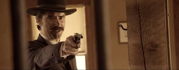 Movie still from “Dead for a Dollar” (2022), directed by Walter Hill – A man holding a gun pointed at the camera; Close Up shot, Over the shoulder angle