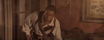 Movie still from “Dead for a Dollar” (2022), directed by Walter Hill – A man in a white dress shirt and a red bow tie; Medium shot, Low angle