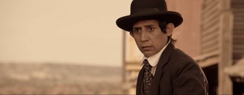 Movie still from “Dead for a Dollar” (2022), directed by Walter Hill – A man wearing a suit and a hat looking at the camera; Close Up shot, Over the shoulder angle