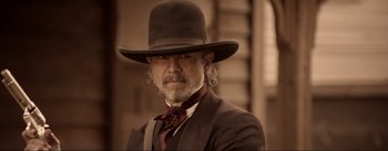 Movie still from “Dead for a Dollar” (2022), directed by Walter Hill – A man in a suit and a hat is posing for a picture; Close Up shot, Over the shoulder angle