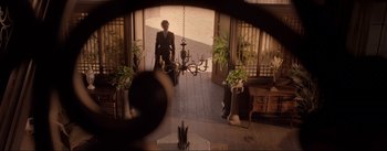 Movie still from “Dead for a Dollar” (2022), directed by Walter Hill – A man riding a bike through a door way; Extreme Wide shot, High angle