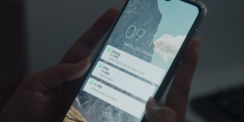 Movie still from “Dear David” (2023), directed by Lucky Kuswandi – A person holding a phone with a notification screen on it; Extreme Close Up shot, High angle