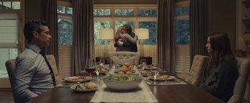 Movie still from “Dear Evan Hansen” (2021), directed by Stephen Chbosky – Two people hug in front of a table filled with plates of food; Wide shot, Low angle