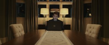Movie still from “Dear Evan Hansen” (2021), directed by Stephen Chbosky – A man sitting in front of a laptop computer on top of a wooden table; Medium shot, High angle