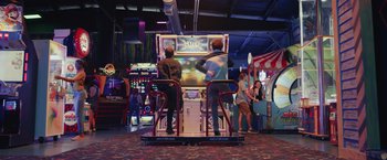 Movie still from “Dear Evan Hansen” (2021), directed by Stephen Chbosky – Two men playing a video game in a game room; Wide shot, Over the shoulder angle