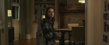 Movie still from “Dear Evan Hansen” (2021), directed by Stephen Chbosky – A woman standing in a room holding a guitar case; Medium shot, Over the shoulder angle