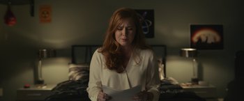 Movie still from “Dear Evan Hansen” (2021), directed by Stephen Chbosky – A red headed woman is holding a sheet of paper in her hands; Medium shot, Over the shoulder angle
