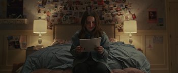 Movie still from “Dear Evan Hansen” (2021), directed by Stephen Chbosky – A woman sitting on a bed looking at a paper; Medium shot, Over the shoulder angle