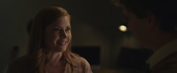 Movie still from “Dear Evan Hansen” (2021), directed by Stephen Chbosky – A young woman smiling for the camera in a dark room; Close Up shot, Over the shoulder angle