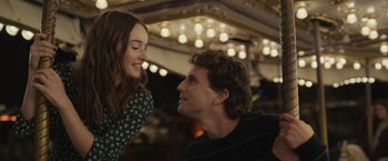Movie still from “Dear Evan Hansen” (2021), directed by Stephen Chbosky – A man and a woman smiling at each other in front of lights; Medium shot, Over the shoulder angle