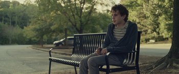 Movie still from “Dear Evan Hansen” (2021), directed by Stephen Chbosky – A man sitting on top of a bench in a park; Medium shot, Over the shoulder angle