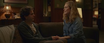 Movie still from “Dear Evan Hansen” (2021), directed by Stephen Chbosky – A man and a woman sitting on a couch holding hands; Medium shot, Over the shoulder angle