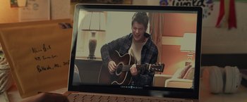 Movie still from “Dear Evan Hansen” (2021), directed by Stephen Chbosky – A man playing an acoustic guitar while sitting in front of a computer screen; Extreme Close Up shot, Over the shoulder angle