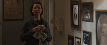 Movie still from “Two Lovers” (2008), directed by James Gray – A woman standing in front of a tv holding a pair of handkerchiefs; Medium shot, Over the shoulder angle
