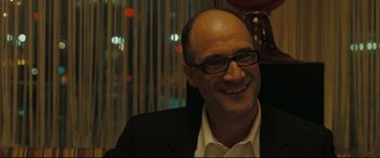 Movie still from “Two Lovers” (2008), directed by James Gray – A man in a suit and glasses smiling for the camera; Close Up shot, Over the shoulder angle