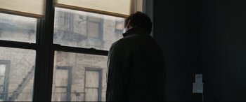 Movie still from “Two Lovers” (2008), directed by James Gray – A man standing in front of a window looking outside; Medium shot, Over the shoulder angle