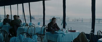 Movie still from “Two Lovers” (2008), directed by James Gray – A woman sitting at a table in front of a large window; Wide shot, Over the shoulder angle