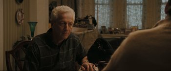 Movie still from “Two Lovers” (2008), directed by James Gray – An older man sitting at a table with a cup of coffee; Medium shot, Over the shoulder angle