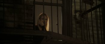 Movie still from “Two Lovers” (2008), directed by James Gray – A woman looking out a window through a fence; Medium shot, Low angle