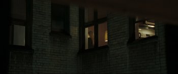 Movie still from “Two Lovers” (2008), directed by James Gray – A person standing in a window at night looking outside; Wide shot, Over the shoulder angle