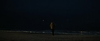 Movie still from “Two Lovers” (2008), directed by James Gray – A person walking on the beach at night; Extreme Wide shot, Over the shoulder angle