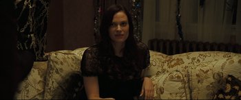 Movie still from “Two Lovers” (2008), directed by James Gray – A woman sitting on top of a couch in front of a window; Medium shot, Over the shoulder angle