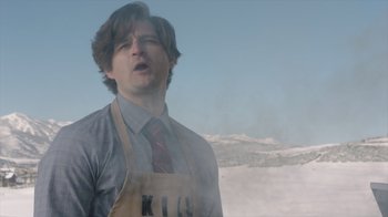 Movie still from “Deborah” (2022), directed by Noga Pnueli – A man wearing an apron and a red tie; Close Up shot, Low angle