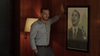 Movie still from “Deborah” (2022), directed by Noga Pnueli – A man standing in front of a picture of obama; Medium shot, Over the shoulder angle