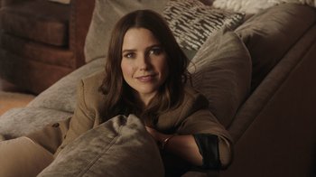 Movie still from “Deborah” (2022), directed by Noga Pnueli – A beautiful woman laying on a couch in a room; Close Up shot, Over the shoulder angle