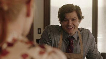 Movie still from “Deborah” (2022), directed by Noga Pnueli – A man wearing an apron smiles at the camera; Close Up shot, Over the shoulder angle