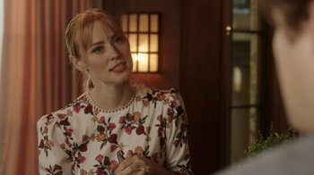 Movie still from “Deborah” (2022), directed by Noga Pnueli – A woman with red hair wearing a white and red floral dress; Close Up shot, Over the shoulder angle