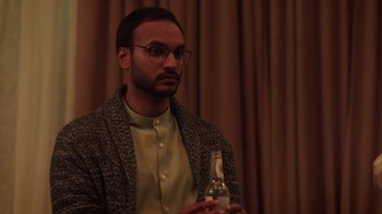 Movie still from “Deborah” (2022), directed by Noga Pnueli – A man with glasses is holding a bottle; Close Up shot, Over the shoulder angle