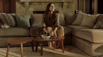 Movie still from “Deborah” (2022), directed by Noga Pnueli – A woman sitting on a couch in a living room; Wide shot, Low angle