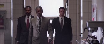 Movie still from “Deep Impact” (1998), directed by Mimi Leder – A man in a suit and tie holding hands with another man in a suit and tie; Medium shot, Low angle