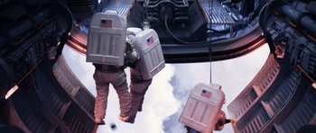 Movie still from “Deep Impact” (1998), directed by Mimi Leder – Two people in spacesuits standing next to each other on a platform; Wide shot, Overhead angle