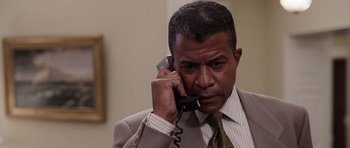 Movie still from “Deep Impact” (1998), directed by Mimi Leder – A man wearing a suit and tie talking on a phone; Close Up shot, Low angle